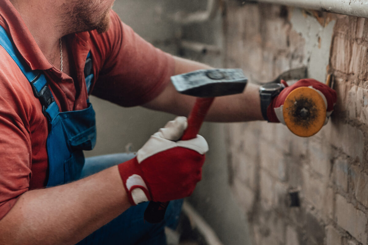 Arbeiter schlägt alten Putz von der Wand Arbeiter schlägt alten Putz von der Wand